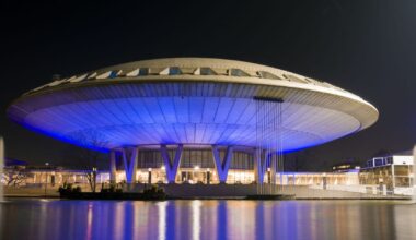 Edifício futurista iluminado à noite com luzes azuis.