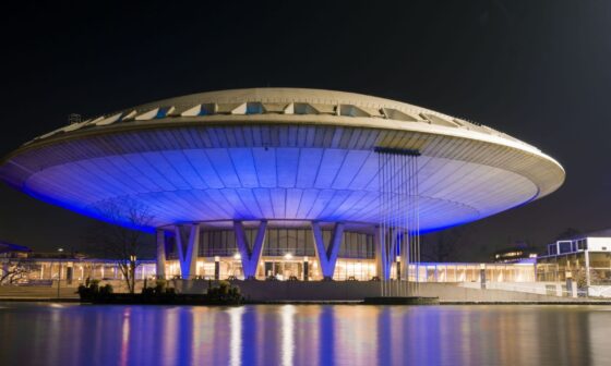 Edifício futurista iluminado à noite com luzes azuis.